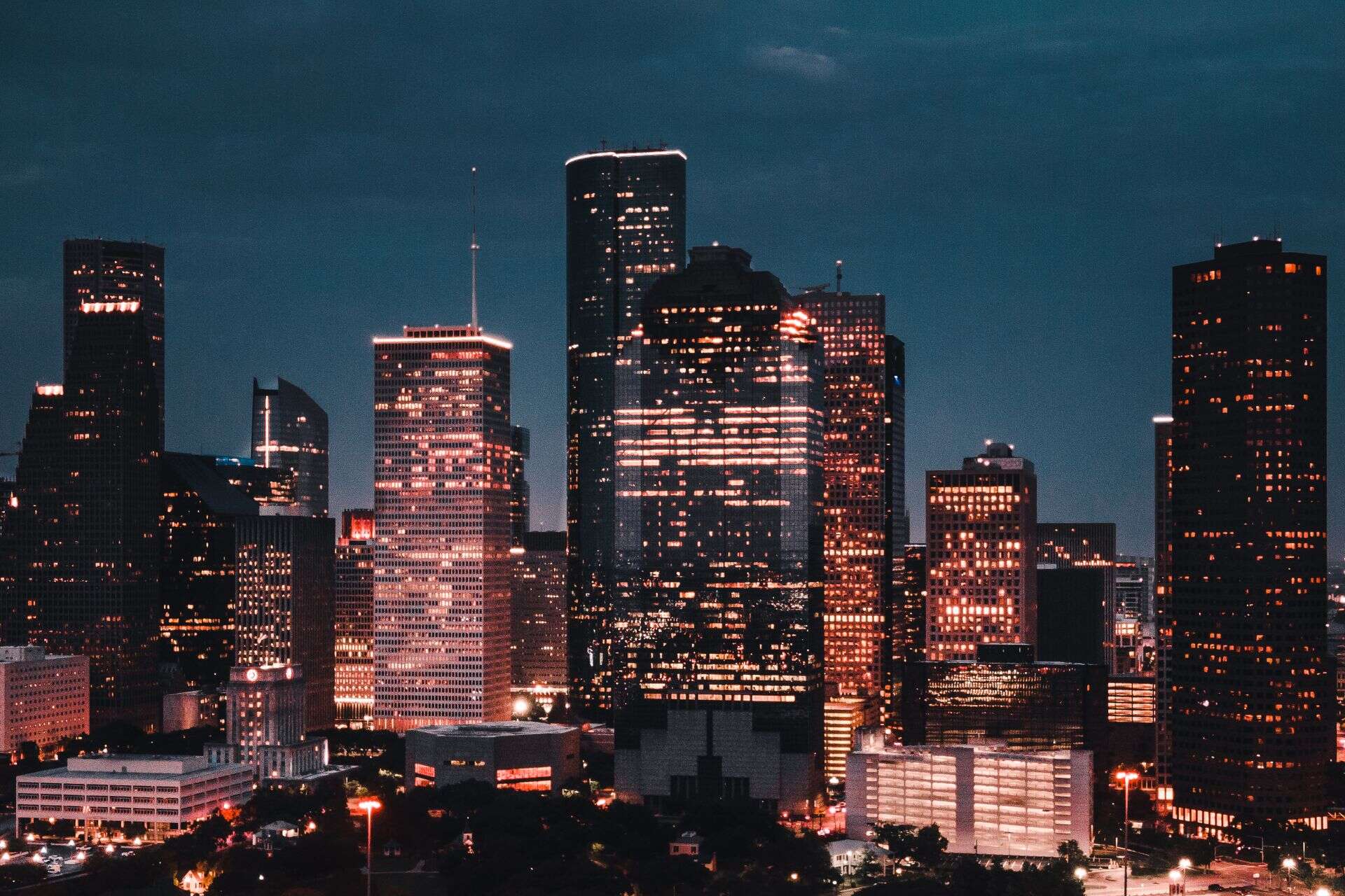 Downtown Houston skyline lit up at dusk, with highway interchanges in the foreground
