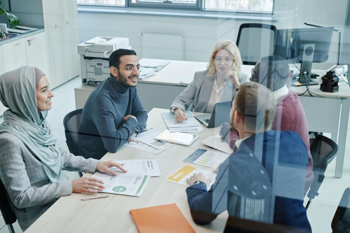 A group of professionals discussing printed reports around a table in a bright office